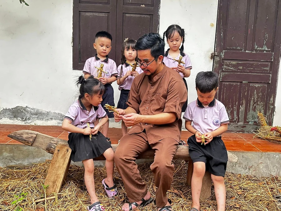 Nghệ nhân Nguyễn Tấn Phát hướng dẫn các em nhỏ làm hình nộm từ rơm.