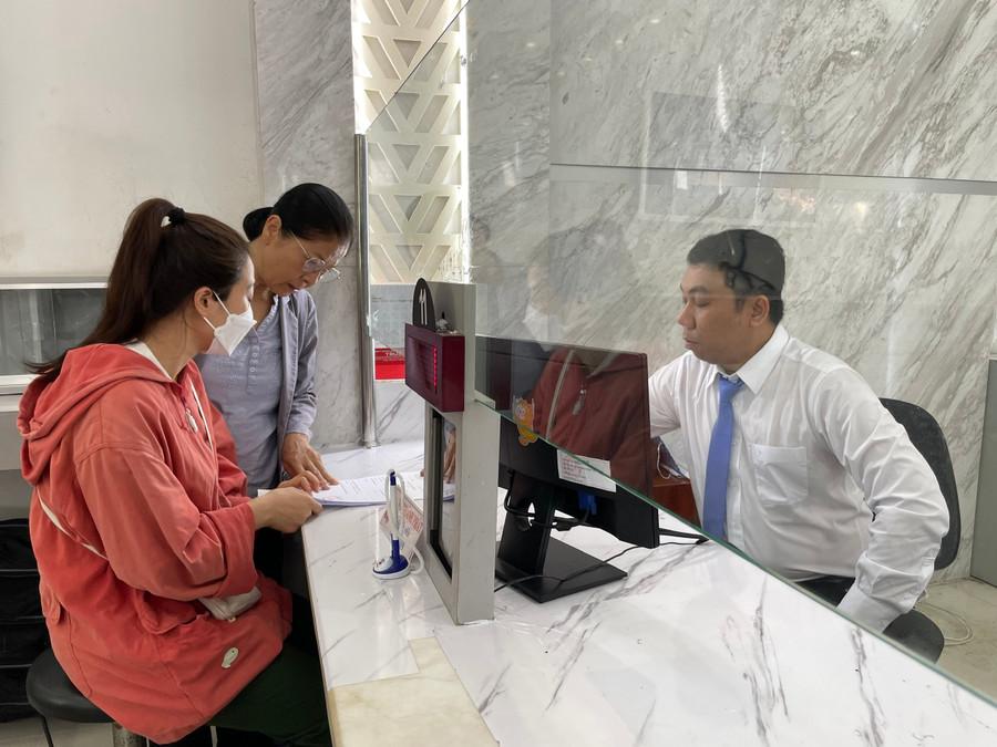Công chức Võ Thanh Phát tại Trung tâm phục vụ hành chính công phường Sài Gòn hướng dẫn thủ tục cho người dân sáng 1/7. (Ảnh: Hà An)