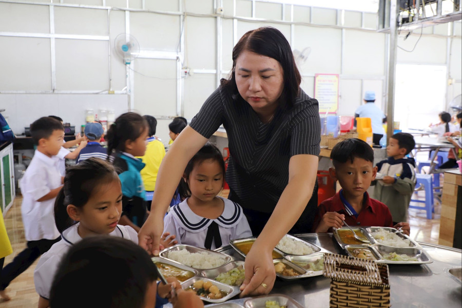 Cô Dung lấy cơm cho các em.