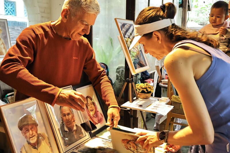 Một số người nước ngoài đang sinh sống tại Hội An cũng tham gia chợ phiên với các sản phẩm như tranh vẽ, bao lì xì... Ảnh: Diễm Phúc