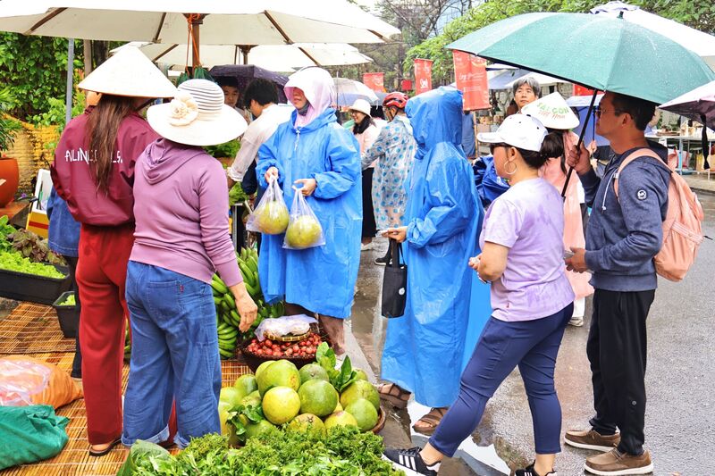 Mặc dù trời mưa, nhưng người dân vẫn tham gia phiên chợ, tập nập mua sắm. Ảnh: Diễm Phúc
