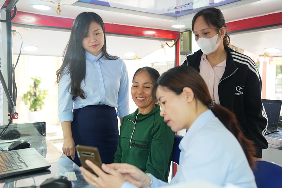 Người dân xã đảo Minh Châu (Hà Nội) được cán bộ Trung tâm Phục vụ hành chính công TP Hà Nội hướng dẫn làm thủ tục trên chiếc xe lưu động, một trong những hoạt động của mô hình “Dịch vụ công lưu động”