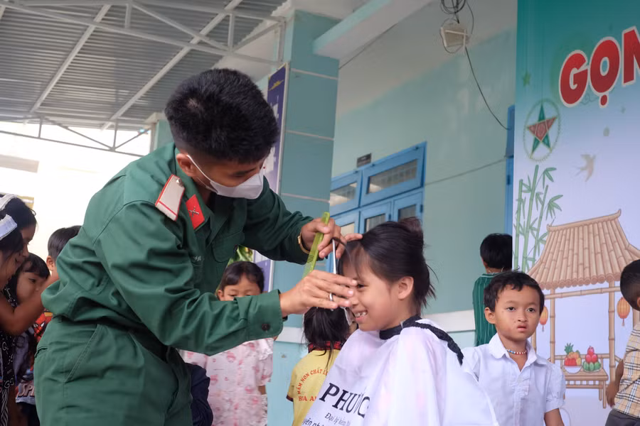 Học sinh vùng cao thích thú với mái tóc mới từ bàn tay người lính. Ảnh: Hoàng Vinh